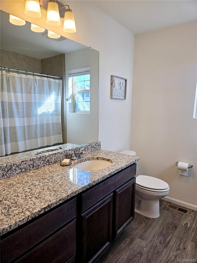 bathroom with toilet, wood finished floors, visible vents, vanity, and baseboards