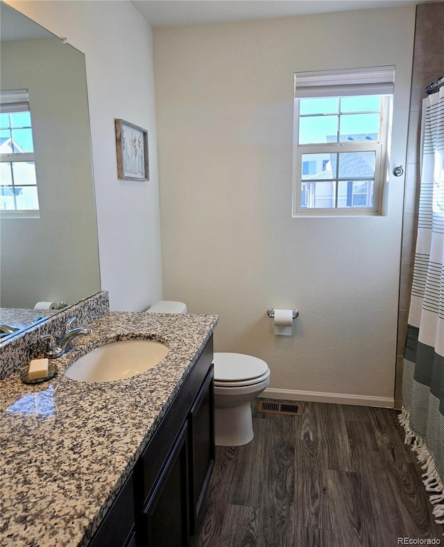 bathroom featuring visible vents, toilet, vanity, wood finished floors, and baseboards