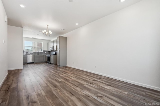 unfurnished living room with an inviting chandelier, sink, and dark hardwood / wood-style flooring