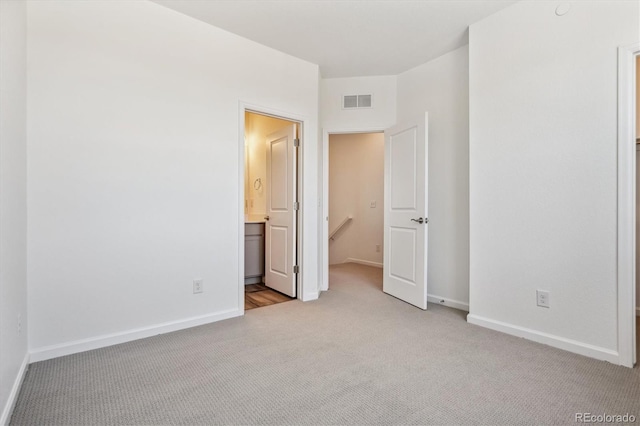 unfurnished bedroom with ensuite bath and light colored carpet