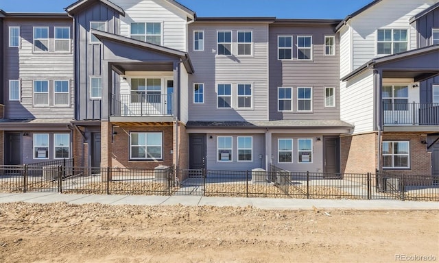 townhome / multi-family property with board and batten siding, brick siding, and a fenced front yard