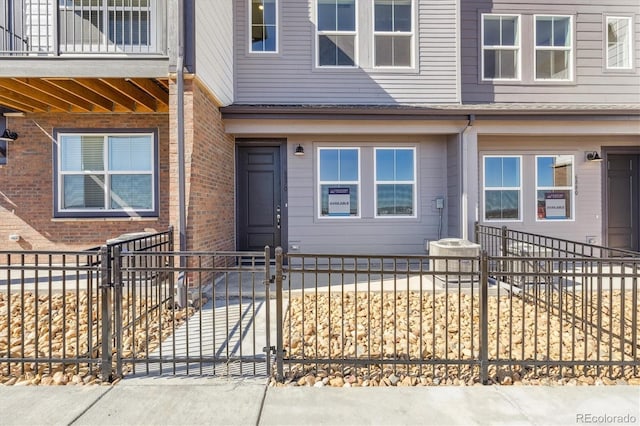 view of exterior entry featuring a gate, brick siding, and fence