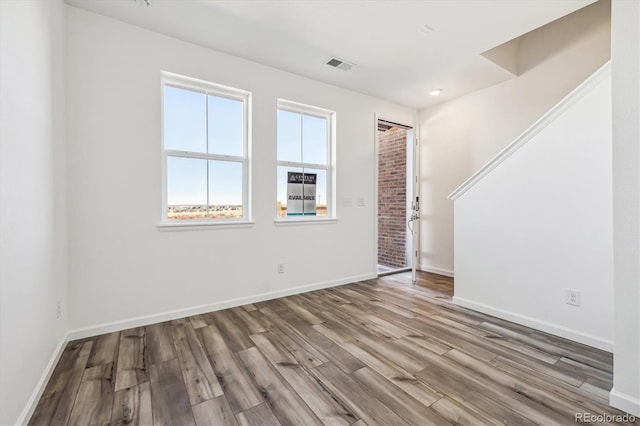 unfurnished room featuring visible vents, baseboards, and wood finished floors