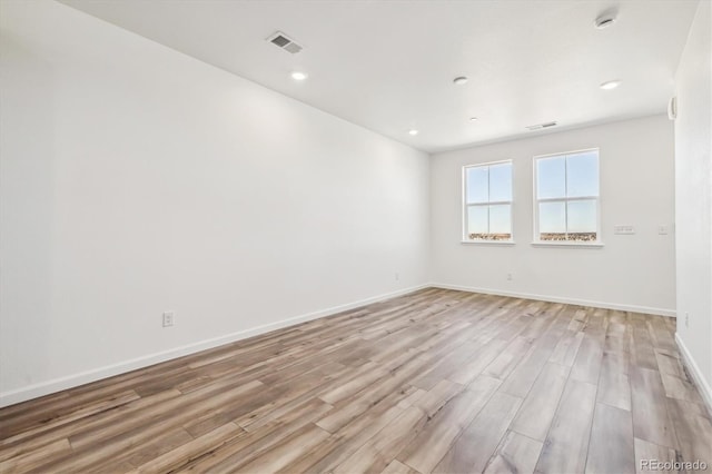 empty room with light wood finished floors, recessed lighting, visible vents, and baseboards