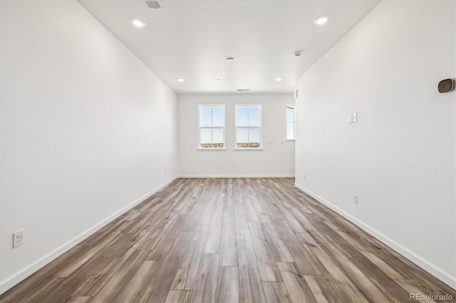 spare room with recessed lighting, baseboards, and wood finished floors