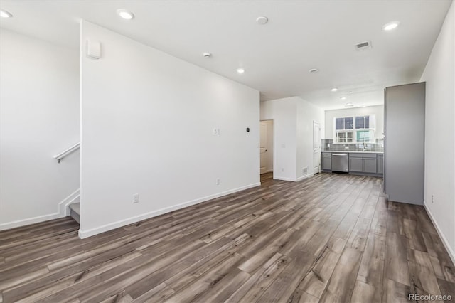 unfurnished living room with dark wood-style flooring, recessed lighting, visible vents, baseboards, and stairs