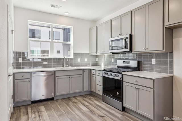 kitchen featuring appliances with stainless steel finishes, a sink, and gray cabinetry