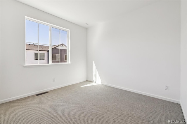 carpeted spare room with visible vents and baseboards