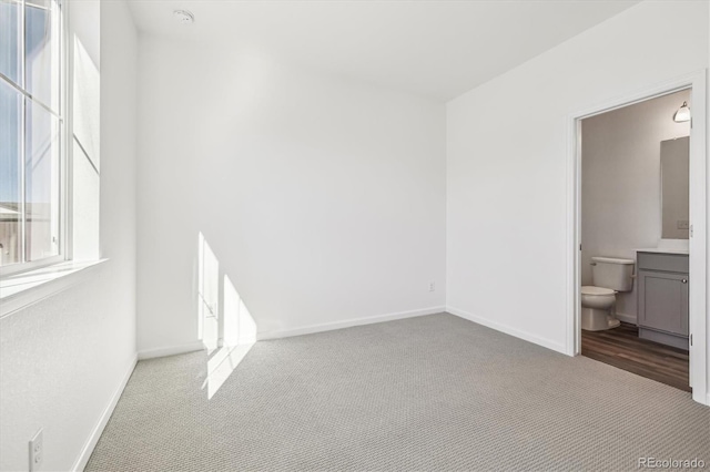 unfurnished bedroom with carpet flooring, ensuite bath, and baseboards