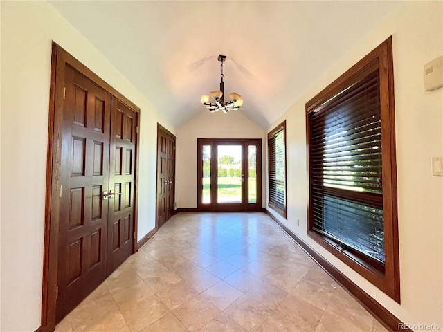 entryway with an inviting chandelier, baseboards, light tile patterned floors, and lofted ceiling