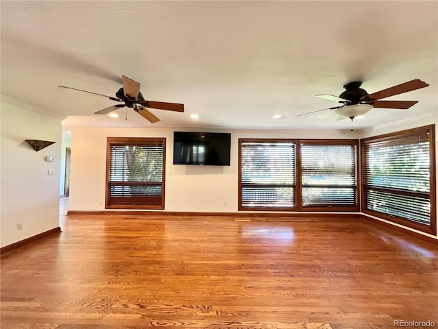 unfurnished living room with baseboards, ceiling fan, ornamental molding, and wood finished floors