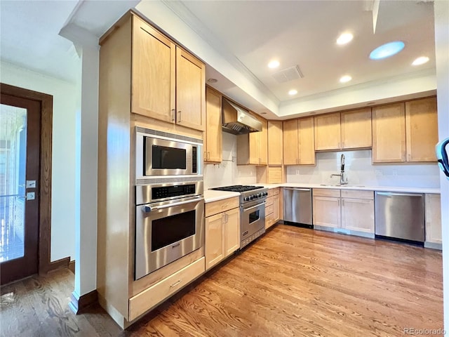 kitchen with light brown cabinetry, appliances with stainless steel finishes, a sink, and range hood