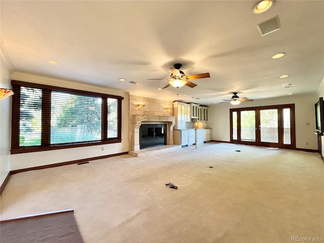 unfurnished living room with visible vents, baseboards, ceiling fan, light colored carpet, and a fireplace with raised hearth