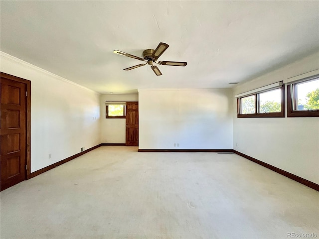spare room featuring a ceiling fan, baseboards, and light colored carpet