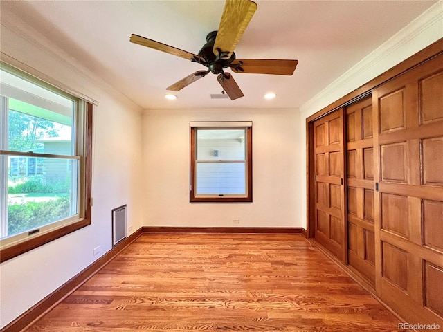unfurnished bedroom featuring crown molding, light wood finished floors, and multiple windows