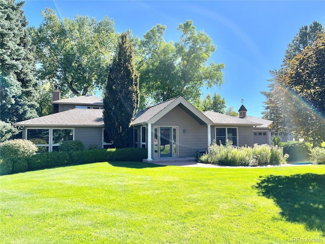 rear view of house with an attached garage and a yard