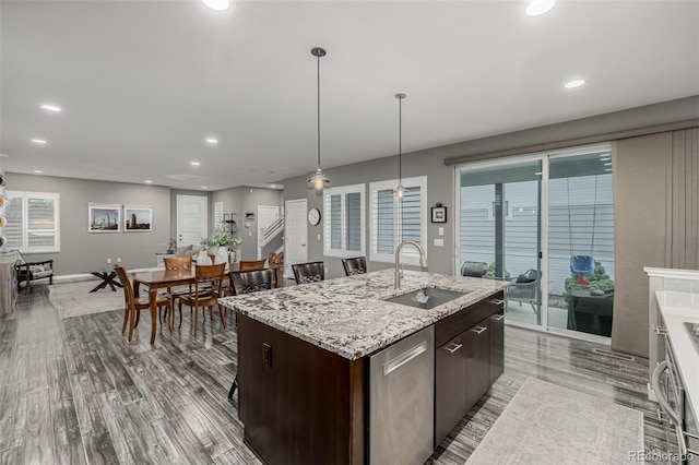 kitchen with a center island with sink, a sink, stainless steel dishwasher, recessed lighting, and dark brown cabinets