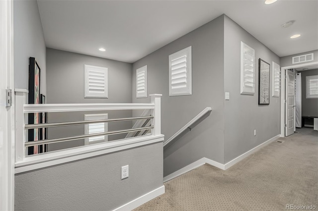 hallway with visible vents, carpet floors, baseboards, recessed lighting, and an upstairs landing