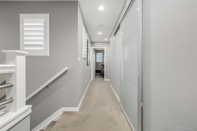 corridor featuring visible vents, baseboards, light colored carpet, an upstairs landing, and recessed lighting