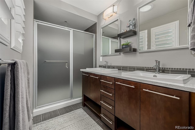full bathroom featuring double vanity, a stall shower, and a sink