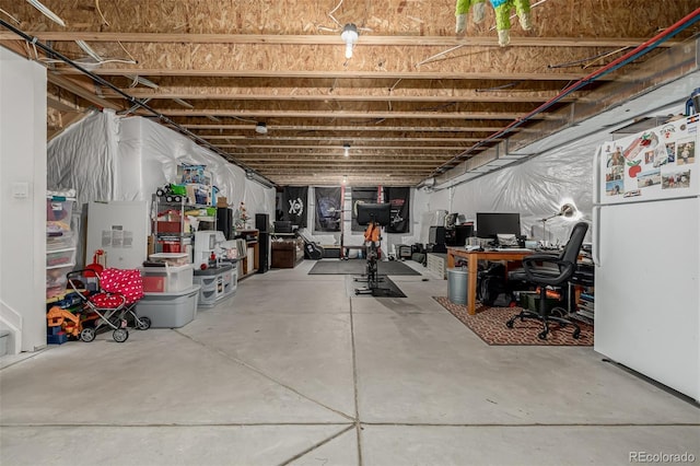 unfinished basement featuring freestanding refrigerator