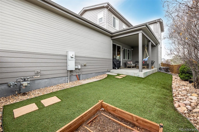 rear view of property featuring fence, a patio area, and a lawn