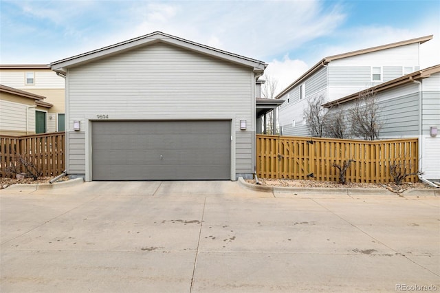 garage with concrete driveway and fence