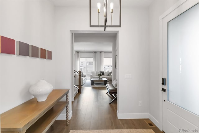 foyer entrance with visible vents, an inviting chandelier, wood finished floors, baseboards, and stairs