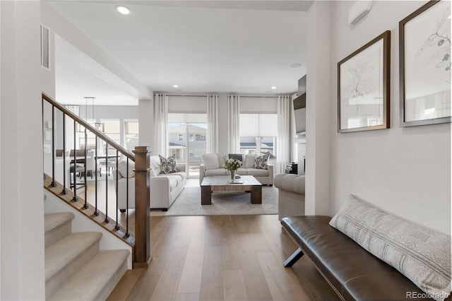 living area with wood-type flooring, visible vents, stairway, and recessed lighting