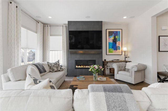 living room with recessed lighting, a large fireplace, baseboards, and wood finished floors