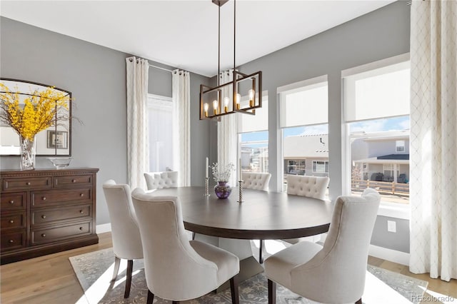 dining room featuring light wood finished floors, baseboards, and a notable chandelier