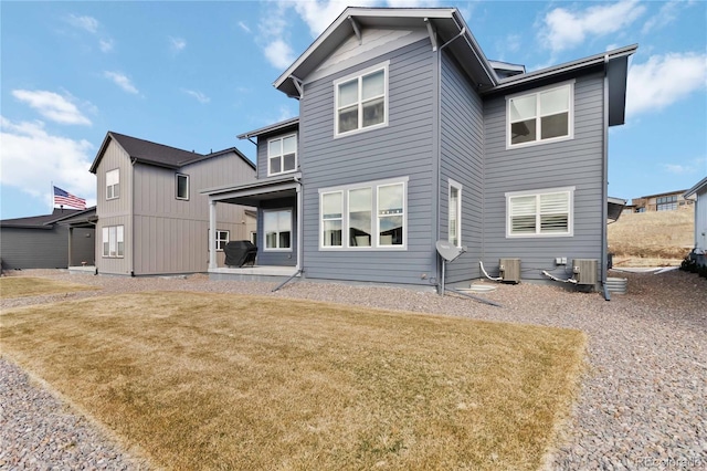 rear view of house with central AC unit, a lawn, and a patio