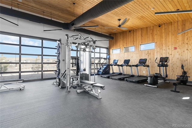 exercise room featuring a high ceiling, wooden ceiling, and wooden walls