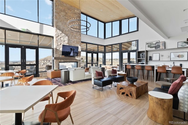living area with a stone fireplace, a healthy amount of sunlight, and a notable chandelier