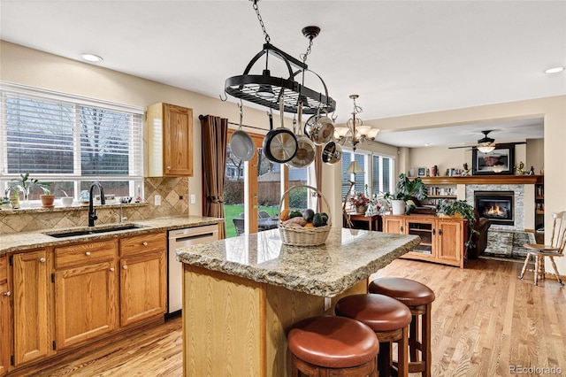 4498 Buena Vista Ct, Castle Rock, CO 80109 - kitchen with dishwasher, a sink, light wood-type flooring, a center island, and decorative backsplash