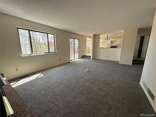 unfurnished living room featuring visible vents, baseboards, dark colored carpet, and a textured ceiling