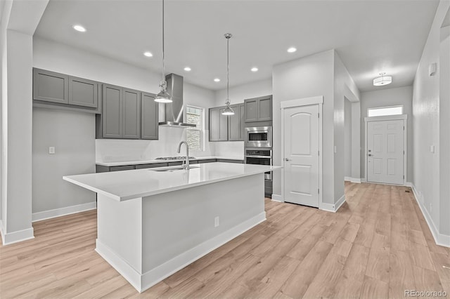21204 E 63rd Dr, Aurora, CO 80019 - kitchen featuring stainless steel appliances, light countertops, gray cabinets, light wood-style floors, and wall chimney exhaust hood