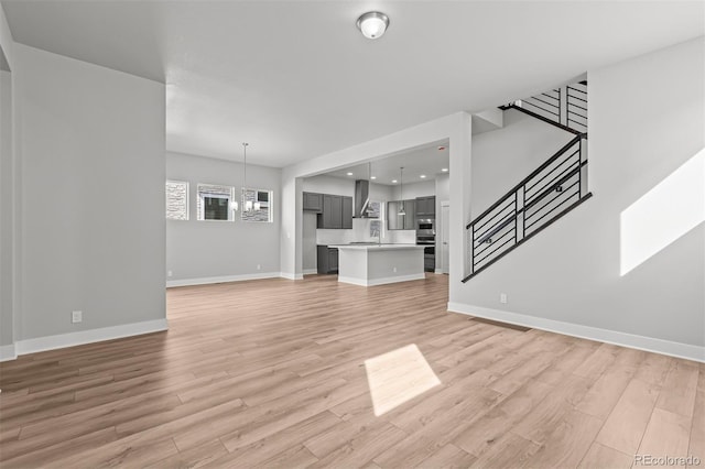 21204 E 63rd Dr, Aurora, CO 80019 - unfurnished living room with recessed lighting, stairway, light wood finished floors, baseboards, and a notable chandelier