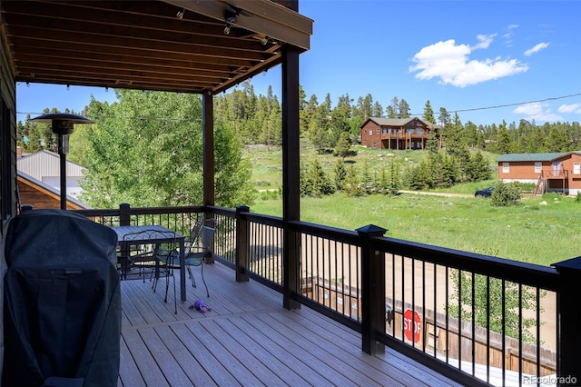 151 County Road 644, Grand Lake, CO 80447 - wooden terrace featuring grilling area, outdoor dining area, view of scattered trees, and a lawn