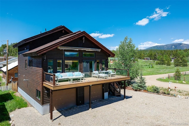 151 County Road 644, Grand Lake, CO 80447 - rear view of house featuring a deck with mountain view, stairway, gravel driveway, an attached garage, and an outdoor hangout area