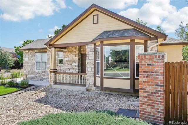 19677 E Vassar Dr, Aurora, CO 80013 - view of front of home featuring stone siding, roof with shingles, and a porch