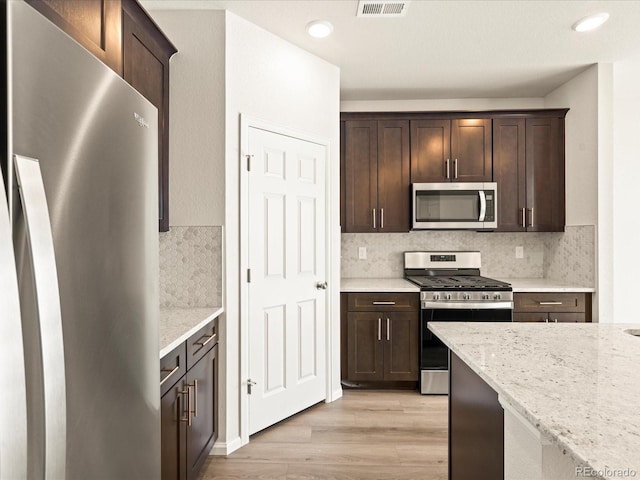 kitchen featuring dark brown cabinetry, appliances with stainless steel finishes, visible vents, and light wood-style flooring
