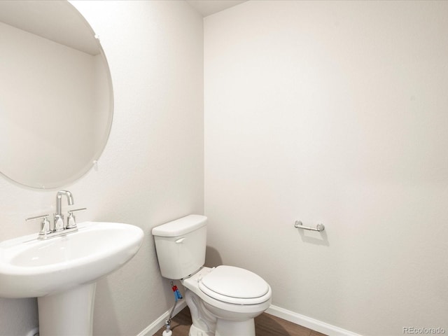 bathroom with wood finished floors, baseboards, a sink, and toilet