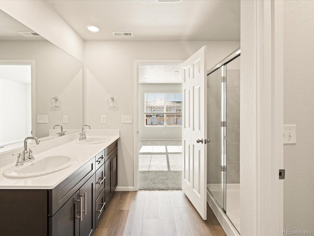 bathroom featuring a shower stall, wood finished floors, a sink, and visible vents
