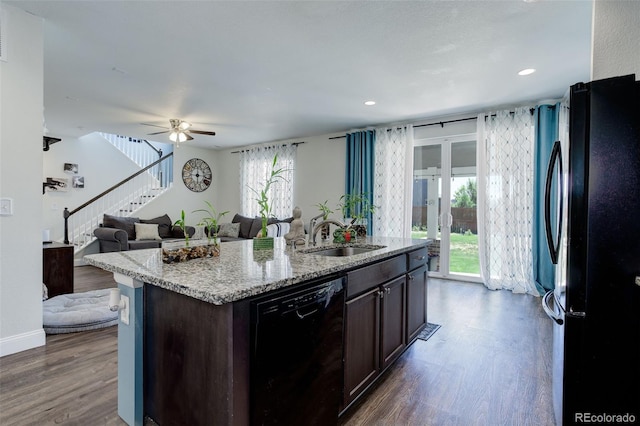 kitchen featuring ceiling fan, a kitchen island with sink, sink, black appliances, and dark hardwood / wood-style floors