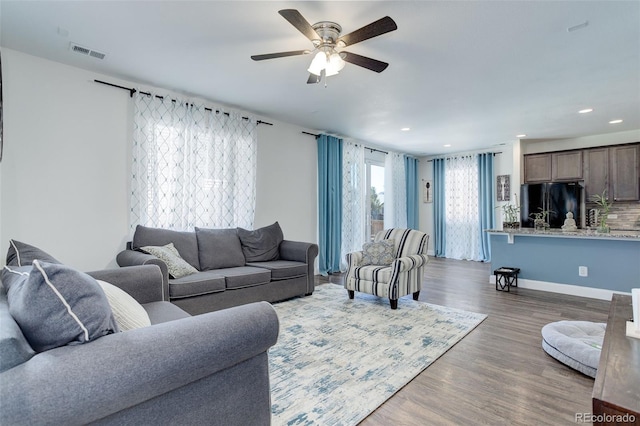 living room with dark hardwood / wood-style flooring and ceiling fan