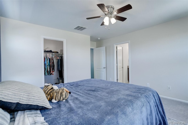 carpeted bedroom featuring a walk in closet, a closet, and ceiling fan