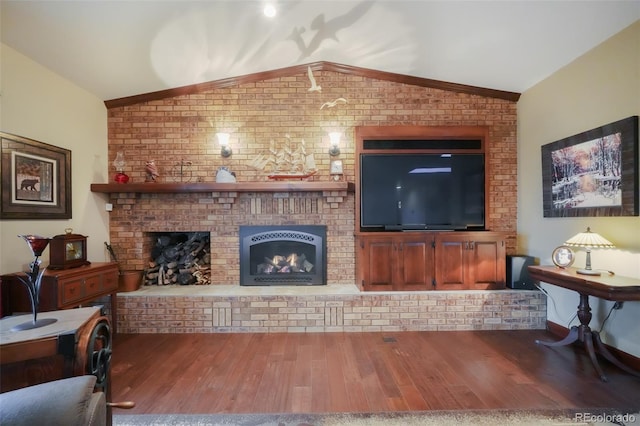 living room with a brick fireplace, vaulted ceiling, brick wall, and wood finished floors