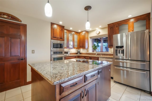 kitchen featuring light stone counters, a center island, light tile patterned floors, appliances with stainless steel finishes, and glass insert cabinets