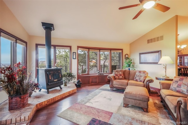 living area with a wood stove, wood-type flooring, visible vents, and vaulted ceiling